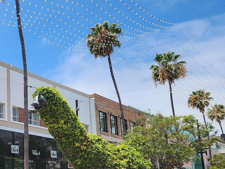 A topiary dinosaur and palm trees on the Third Street Promenade