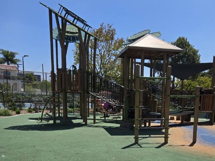 Wooden play towers under a clear sky at Douglas Park
