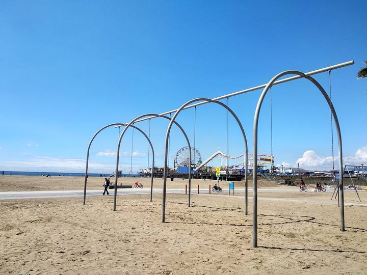 Swing rings on the sand at Original Muscle Beach, with the pier behind