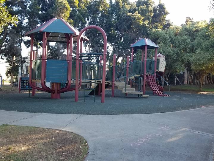 A play structure under shade trees at Gandara Park