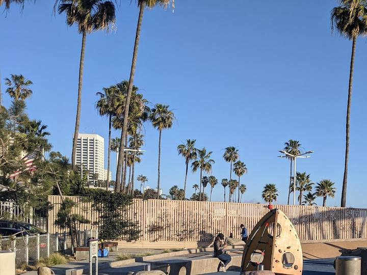 A beach playground with palm trees and a downtown tower behind it